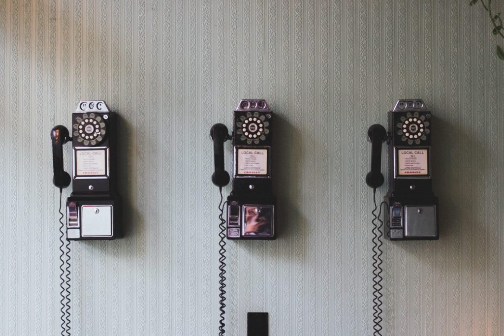3 rotary pay phones hang on a white wall