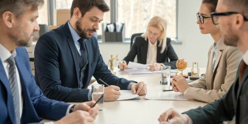 Group of business people sitting at the table and making notes at the table during a business meeting at office